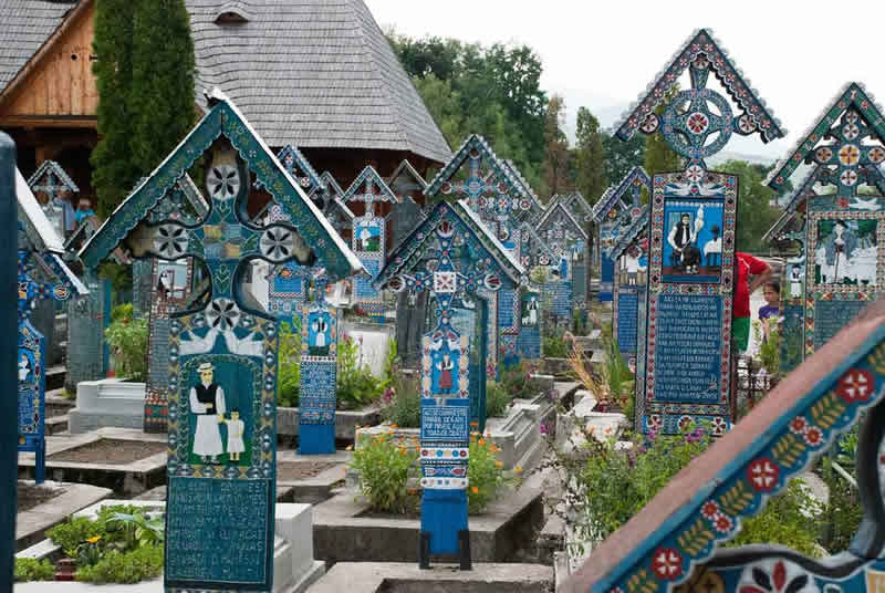 Imagine ce reprezinta un ansamblu de cruci si morminte din Cimitirul Vesel de la Sapanta